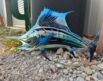 Puede incluir: Una escultura de metal azul y verde de un pez marlin. La escultura está detallada con escamas y aletas. Es una pieza decorativa para un hogar o jardín.