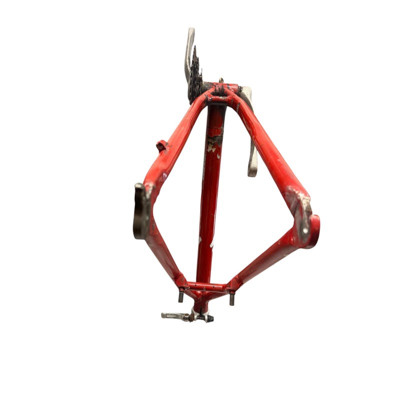 Puede incluir: Un cuadro de bicicleta rojo vintage con desgaste visible. El cuadro met&aacute;lico tiene un dise&ntilde;o triangular, con puntos de fijaci&oacute;n para ruedas, sill&iacute;n y manillar. El cuadro est&aacute; aislado sobre un fondo blanco, resaltando su dise&ntilde;o y estado.