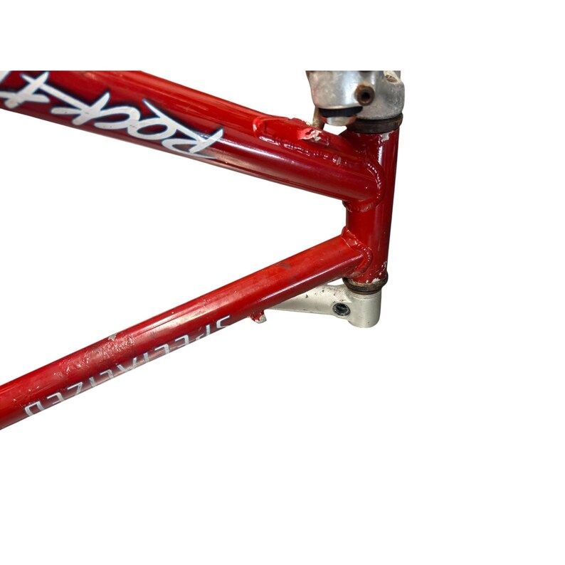 Puede incluir: Cuadro de bicicleta Specialized Rockhopper rojo con componentes plateados. El cuadro tiene letras blancas que dicen "Rock" y "Specialized". El cuadro es de metal y tiene forma triangular.