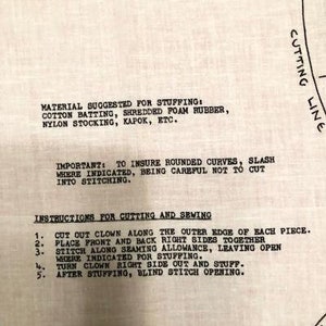 May include: Black and white instructions for sewing a clown doll. The instructions include a list of materials suggested for stuffing, such as cotton batting, shredded foam rubber, nylon stocking, kapok, and more. The instructions also include steps for cutting and sewing the clown doll.