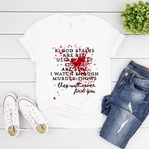 Può includere: Maglietta bianca con un design di schizzi di sangue rosso e il testo "BLOOD STAINS ARE RED ULTRAVIOLET LIGHTS ARE BLUE I WATCH ENOUGH MURDER SHOWS they will never find you"
