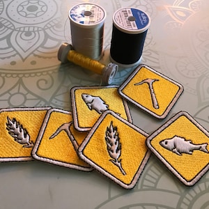 May include: Six yellow embroidered patches with white stitching. The patches feature different symbols, including a fish, a wheat stalk, a pickaxe, and a fish. The patches are arranged in a pile on a gray surface.
