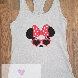 May include: Gray tank top with a red and white Minnie Mouse graphic wearing heart-shaped sunglasses. The graphic includes a red bow with white polka dots. The text "M&I Magical Designs" and a website address are printed on the bottom of the shirt.
