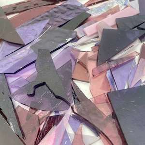 May include: A pile of purple and pink glass shards, some with iridescent finishes, for crafting or mosaic projects.