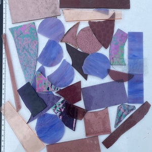 May include: Assortment of purple, pink, and brown stained glass pieces in various shapes and sizes, including circles, triangles, and rectangles.