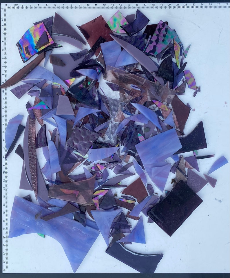 May include: A collection of purple, iridescent, and black glass shards. The shards are various shapes and sizes, and some have a textured surface.