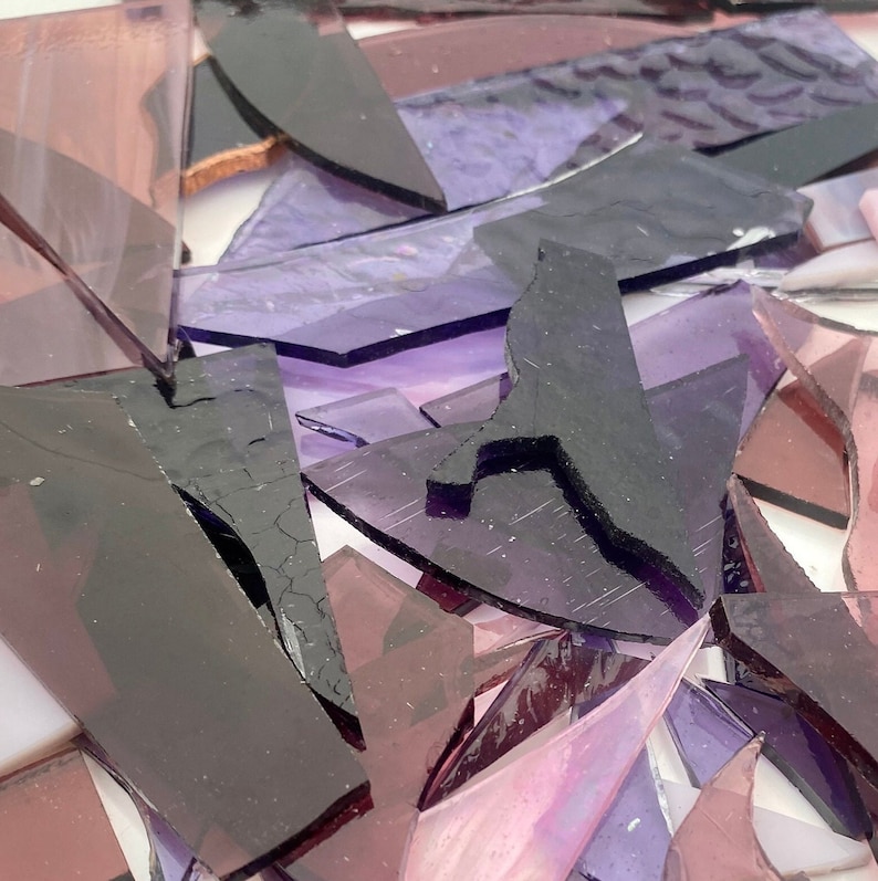 May include: A pile of purple and pink glass shards, some with a textured surface, and a black silhouette of a bird.