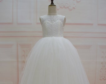 May include: A white sleeveless tulle dress with a lace bodice. The dress has a full skirt and a round neckline.