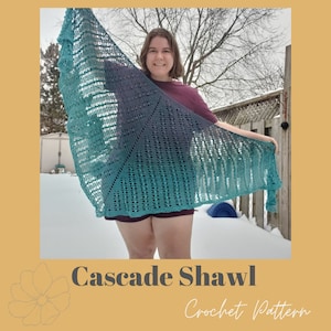 May include: A teal and purple gradient crochet shawl with a cascading stitch pattern. The shawl is held by a person in a snowy outdoor setting. The text "Cascade Shawl Crochet Pattern" is displayed below the image.