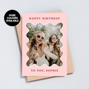 Op de afbeelding: Roze verjaardagskaart met een foto van twee mensen met een zonnebril. De kaart heeft de tekst "Happy Birthday" en "To You, Sophie" in het rood. Een zwarte cirkel met witte tekst zegt "More Colours Available".