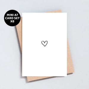 Puede incluir: Una tarjeta blanca con una pequeña ilustración de corazón negro, colocada sobre un sobre marrón. Un círculo negro con texto blanco dice "MINI A7 CARD SET X8". El juego de tarjetas es probablemente para enviar notas o mensajes cortos.