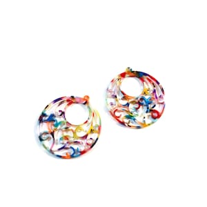 May include: A pair of colourful, round earrings with a filigree design. The earrings are made of a translucent material with a mix of red, blue, green, yellow, and purple colours.