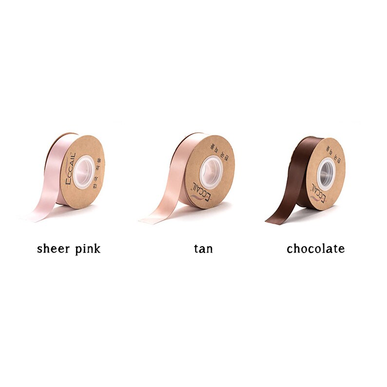 May include: Three spools of ribbon in different colors: sheer pink, tan, and chocolate. Each spool is wrapped in brown paper with the word "ECCAIL" printed on it.
