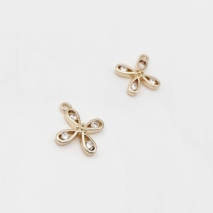 May include: Two gold-tone flower charms with clear crystal accents. Each charm has four petals and a loop for attaching to jewellery.