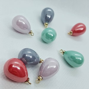 Puede incluir: Una colección de cuentas brillantes en forma de gota y redondas, en tonos rosa, gris, rojo y verde. Cada cuenta tiene un lazo dorado para ensartar. Medidas en centímetros.