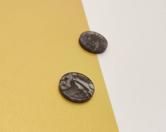 May include: Two round, black and white patterned resin earrings. The earrings have a marbled look with brown veins.