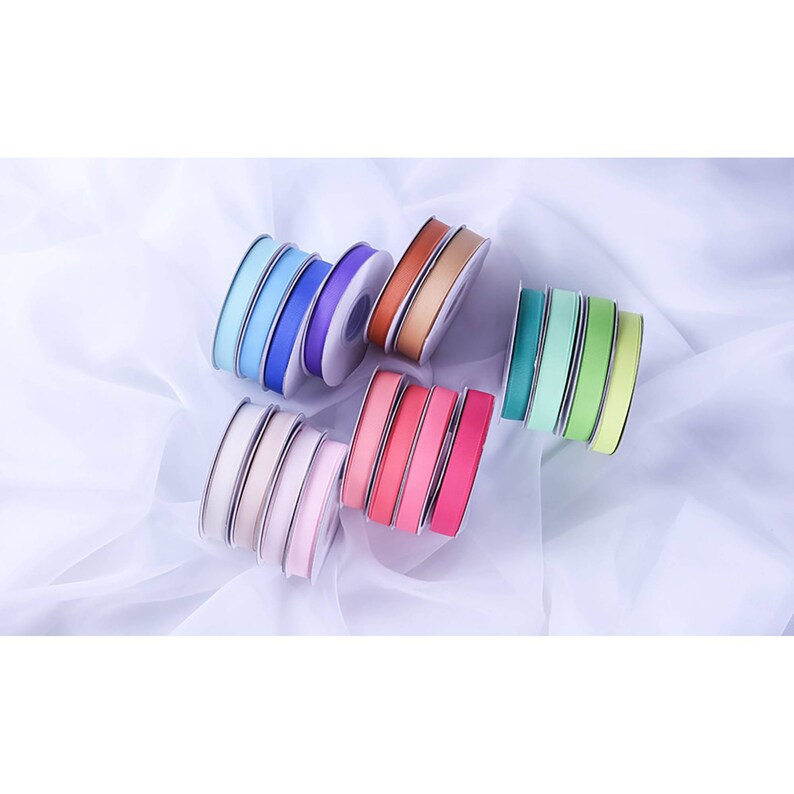 May include: Assortment of colorful satin ribbon spools in various shades of blue, green, pink, red, and brown. The ribbon is wound around spools with a white center.