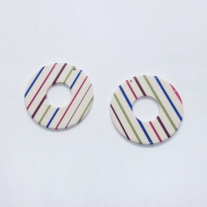 An ivory acetate pendant with vibrant multi-colored candy stripes in a bold graphic pattern.