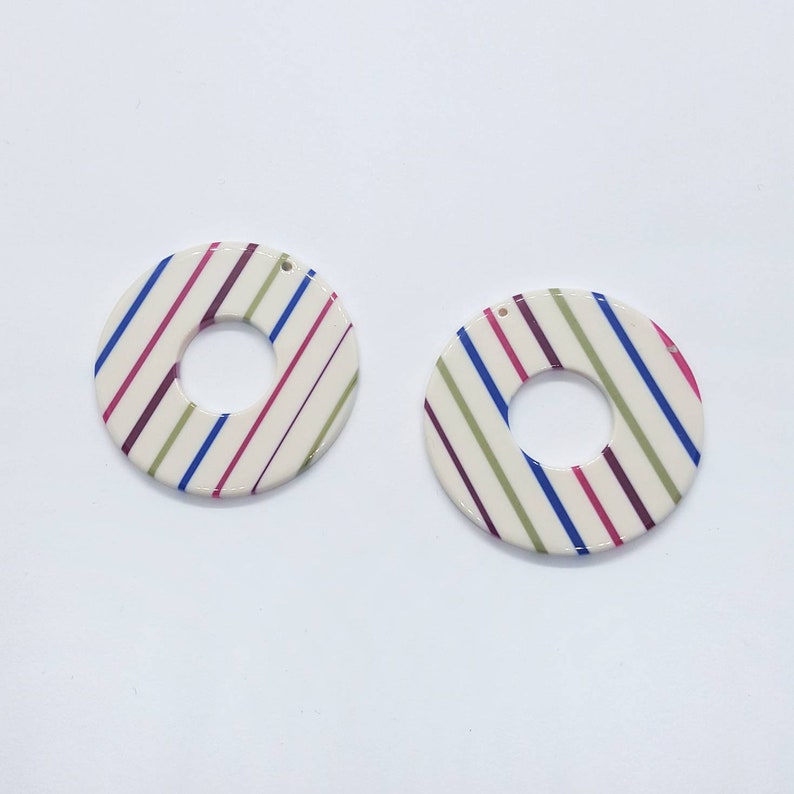 An ivory acetate pendant with vibrant multi-colored candy stripes in a bold graphic pattern.