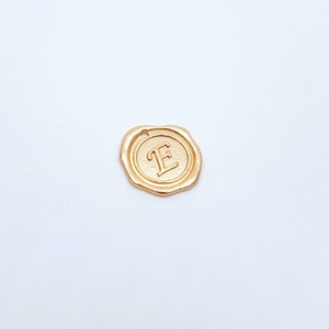 May include: Gold-coloured wax seal with the letter "E" embossed in the centre.