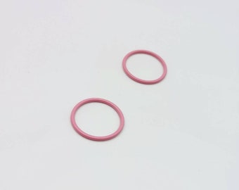 Può includere: Due anelli di metallo rosa, uno leggermente più grande dell'altro, su uno sfondo bianco.