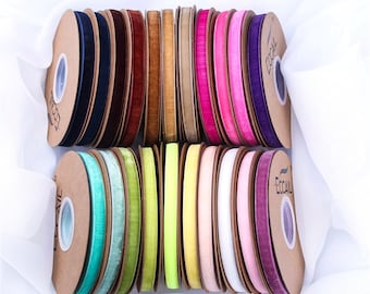 May include: Assortment of 18 spools of velvet ribbon in various colors, including navy blue, burgundy, brown, beige, pink, green, yellow, and purple. Each spool is wrapped in brown paper with the word "ECCOAIL" printed on it.
