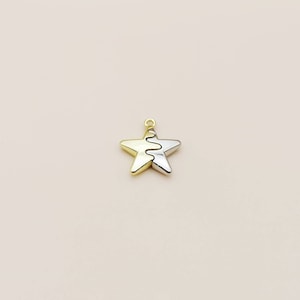 May include: A gold and silver star-shaped charm with a wavy line design. The charm has a small loop at the top for attaching to a necklace or bracelet. The star is divided into two sections, one gold and one silver.