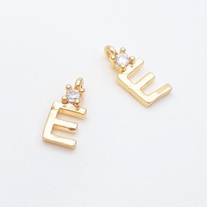 May include: Two gold letter E charms with a clear rhinestone accent. The charms are textured and have a slightly hammered finish.