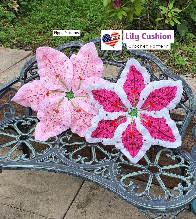 May include: Two crocheted lily flower cushions, one pink and one white with pink accents, on a metal bench. The pink cushion has a white border. The white cushion has a pink center and a white border. The text "Lily Cushion Crochet Pattern" is visible in the image.