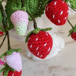 May include: A close-up of a crocheted strawberry bouquet. The strawberries are red with white stitching and green leaves. The bouquet is in a white vase. The text "Pippa Patterns" is visible in the background.