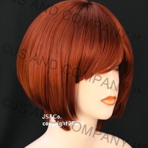 May include: A short, straight, auburn wig with blunt bangs. The wig is styled in a bob shape and has a natural-looking finish.