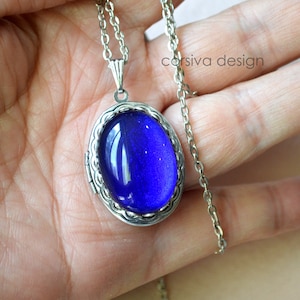 Peut inclure: Un collier avec un pendentif en forme d'ovale en verre bleu. Le pendentif est en argent et a un cadre détaillé. Le collier est en argent.