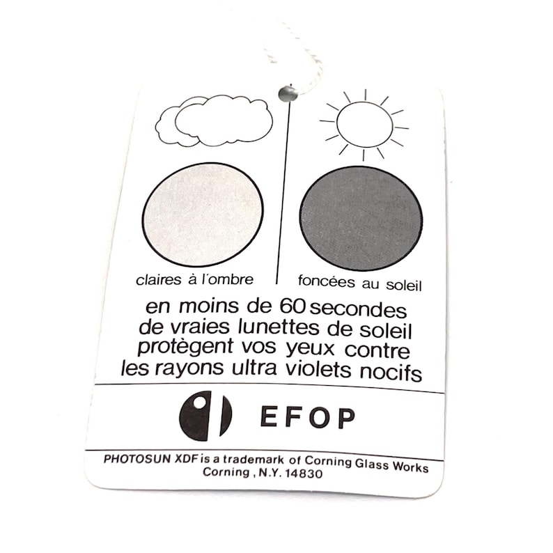 Puede incluir: Etiqueta rectangular blanca con una cuerda, con ilustraciones de una nube y un sol, y texto en franc&eacute;s. El texto describe gafas de sol que se oscurecen con la luz solar y protegen contra los rayos UV. La etiqueta tambi&eacute;n incluye el logotipo de EFOP e informaci&oacute;n de la marca.