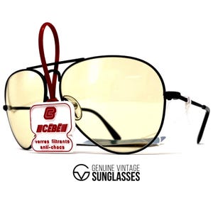 Puede incluir: Gafas de sol de aviador con montura negra y lentes de color amarillo. Una etiqueta roja cuelga de la montura, mostrando el logotipo de la marca y texto. Las gafas de sol est&aacute;n etiquetadas como "Genuine Vintage Sunglasses."