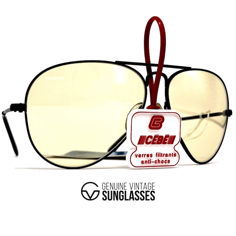 Puede incluir: Gafas de sol de aviador con montura negra y lentes amarillas. Una etiqueta roja con la marca "CEBE" est&aacute; adjunta. El texto "GENUINE VINTAGE SUNGLASSES" est&aacute; impreso debajo.