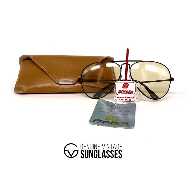 Puede incluir: Gafas de sol aviador negras vintage con lentes de color amarillo, un estuche de cuero marr&oacute;n y una etiqueta del producto. Las gafas de sol tienen un doble puente y un dise&ntilde;o cl&aacute;sico. La etiqueta dice "UCEBEN" y "verres filtrants anti-chocs".