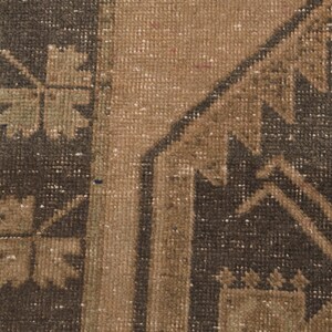 Puede incluir: Primer plano de una alfombra de color marr&oacute;n y negro con un dise&ntilde;o geom&eacute;trico. La alfombra tiene un aspecto desgastado y vintage.