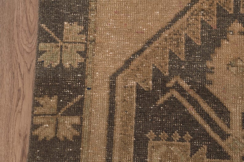 Puede incluir: Primer plano de una alfombra de color marr&oacute;n y negro con un dise&ntilde;o geom&eacute;trico. La alfombra tiene un aspecto desgastado y vintage.
