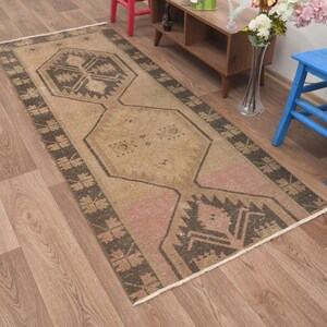 Puede incluir: Una alfombra de pasillo de estilo vintage con un patr&oacute;n geom&eacute;trico en tonos marrones, beige y rosa. La alfombra tiene un aspecto desgastado y es perfecta para a&ntilde;adir un toque de estilo bohemio a cualquier habitaci&oacute;n.