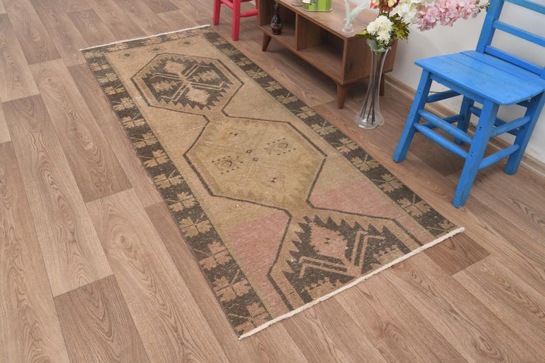 Puede incluir: Una alfombra de pasillo de estilo vintage con un patr&oacute;n geom&eacute;trico en tonos marrones, beige y rosa. La alfombra tiene un aspecto desgastado y es perfecta para a&ntilde;adir un toque de estilo bohemio a cualquier habitaci&oacute;n.