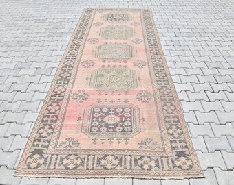 May include: A vintage pink and black patterned rug with a geometric design. The rug has a faded look and is made of wool.
