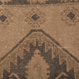 Puede incluir: Primer plano de una alfombra marr&oacute;n y negra con un dise&ntilde;o geom&eacute;trico. La alfombra tiene un aspecto desgastado y vintage.