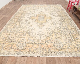 May include: A vintage cream-colored rug with a floral pattern in shades of beige and brown. The rug has a distressed look and a fringed edge.