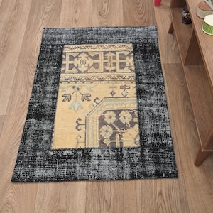 May include: A rectangular, vintage-style rug with a distressed black border and a central panel in shades of beige, brown, and gray. The rug features intricate geometric and floral patterns, adding a touch of traditional elegance to any space.