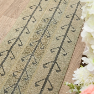 May include: A beige and black patterned rug with a geometric design. The rug is made of woven fabric and has a natural, rustic look.