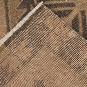 Puede incluir: Primer plano de una alfombra marr&oacute;n y beige con un patr&oacute;n geom&eacute;trico. La alfombra tiene un borde de flecos.