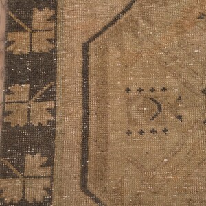 Puede incluir: Primer plano de una alfombra beige con un patr&oacute;n geom&eacute;trico marr&oacute;n. La alfombra tiene un aspecto desgastado y vintage.