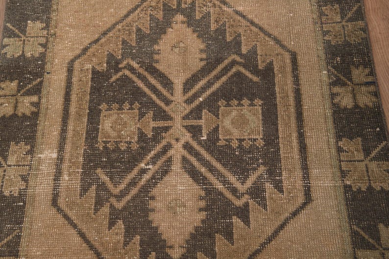 Puede incluir: Una alfombra vintage con un patr&oacute;n geom&eacute;trico marr&oacute;n y beige. La alfombra tiene un aspecto desgastado y envejecido, lo que le da un aspecto r&uacute;stico y antiguo.