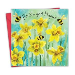 Puede incluir: Una tarjeta de felicitación con una ilustración de acuarela de narcisos amarillos y abejas. La tarjeta tiene el texto "Penblwydd Hapus", que es galés para "Feliz cumpleaños".
