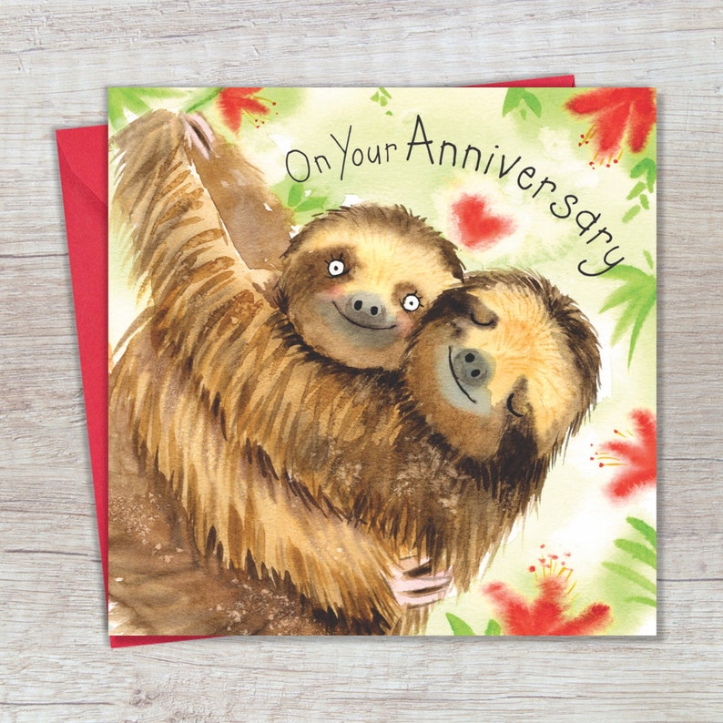May include: A greeting card with a watercolor illustration of two sloths hugging. The card has a green background with red flowers and the text "On Your Anniversary" in black.